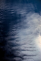 carpet formed by white cirrocumulus clouds with different textures, floating under a navy blue sky.