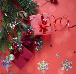 Christmas red gift box with a red bow on a red background. Spruce branch with red berries. Copyspace