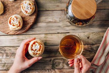 Rolled buns with apple and coconut paste on wooden cutting board with herbal tea. Quick puff pastry for breakfast.