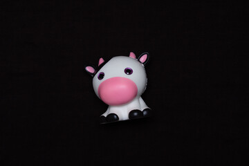 Soft toy cute cow on a dark background.