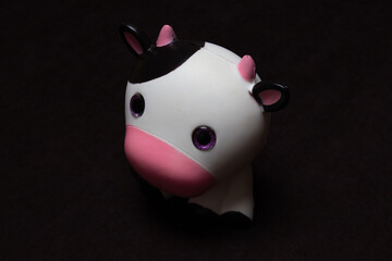 Soft toy cute cow on a dark background.