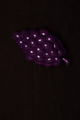 A bunch of toy grapes on a dark background.