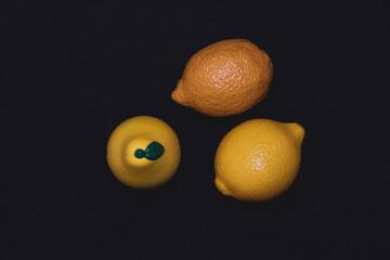 Photos of toy fruits on a dark background. Plastic toy