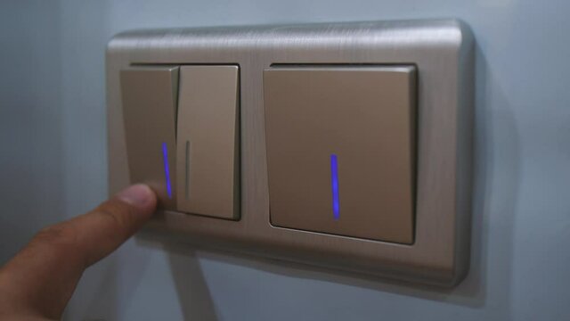 Close up men's hand flips a light switch on and off