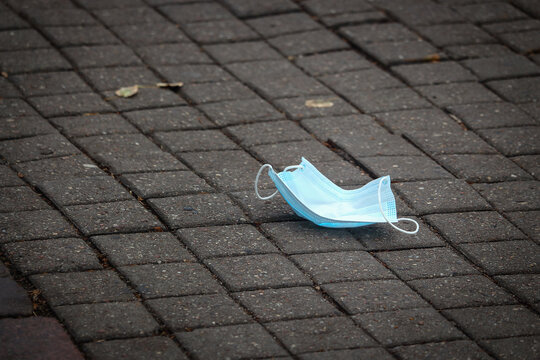 Blue Facial Mask Lying On Wet Pavement