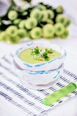 Homemade cream soup with green peas, parsley leaves and alfalfa sprouts on a white background