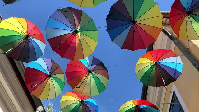 Decorative colorful umbrellas hanging on ropes in the air on blue sky background. Horizontal picture