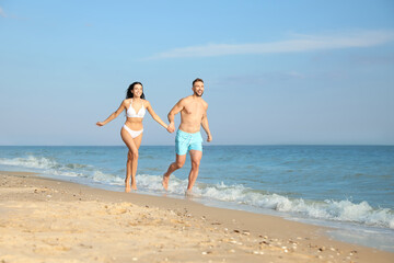 Happy young couple running together on beach