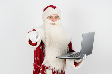 Santa Claus sits at his desk and works at the computer.