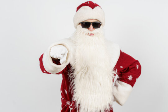Santa Claus in dark glasses points his finger towards the camera. Isolated background. Focusing the image on your finger