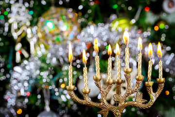 Hanukkah background with menorah and burning candles on sparkle background with defocused lights.