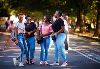 beautiful african american women, laughing friends having fun while walking on the street