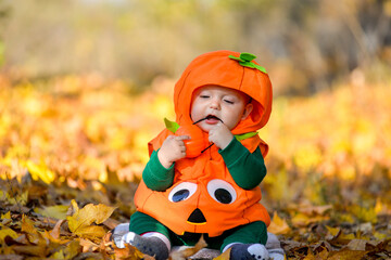 Child in pumpkin suit on background of autumn leaves