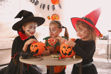 Cute little kids with pumpkin candy buckets wearing Halloween costumes at home