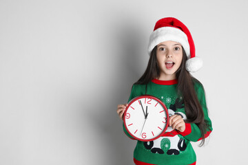 Girl in Santa hat with clock on white background, space for text. Christmas countdown