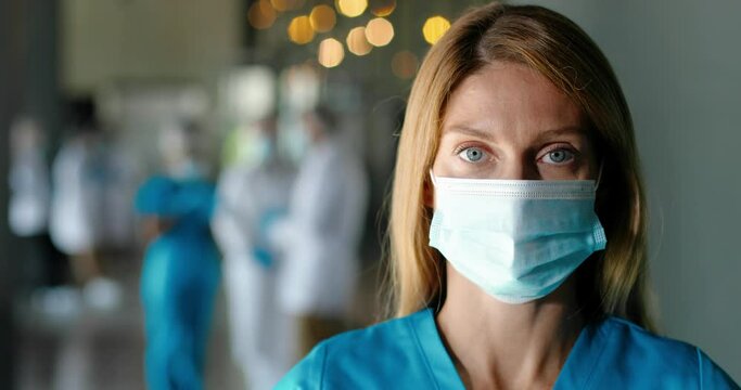 Portrait of tired Caucasian woman doctor in medical mask looking at camera. Close up of female physician. Medic or nurse in clinic. Indoors. Coronavirus concept. Protected. Doc at work.