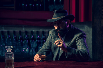 Portrait of a handsome bearded man in elegant suit drinking a Whiskey.