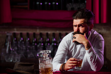 Portrait of a handsome bearded Businessman in elegant suit drinking a Whiskey.