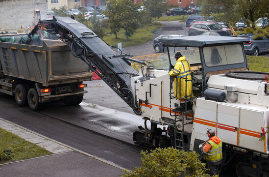Cold milling machine and truck at work removing old asphalt