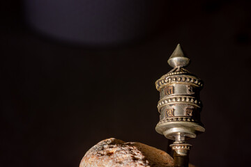Detail of a Tibetan hand prayer wheel between light and shadow