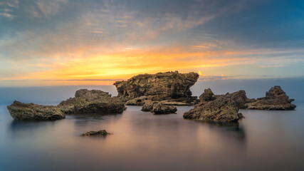 Scenic rock formation in the  Mediterranean sea against a gorgeous sunset.
