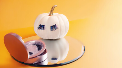 White pumpkin with magnetic fake artificial eyelashes looking in pink mirror kit isolated on orange...