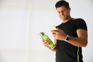 Man with smartphone and fitness tracker indoors. Space for text