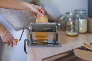 Pressing dough in manual pasta machine.