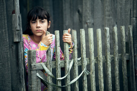 Teen girl standing near vintage rural fence in the village.