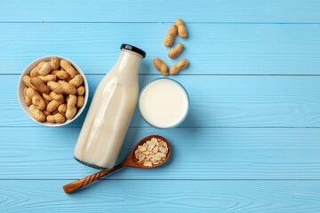 Vegan peanut milk in glass bottle with peanuts on wooden board