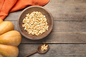 Raw pumpkin seeds on wooden table, flat lay. Space for text