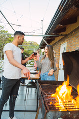 Couple at a barbecue. Young couple drinking wine at a barbecue. Group of friends on the terrace.  Wellness and outdoor concept.