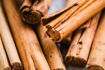 heap of raw brown cinnamon sticks on light background
