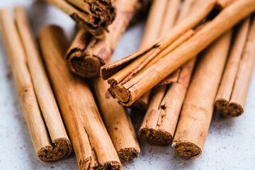 heap of raw brown cinnamon sticks on light background
