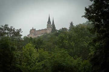 Fototapeta na wymiar santa iglesia de Covadonga vista desde abajo de la montaña en día de niebla y nubes