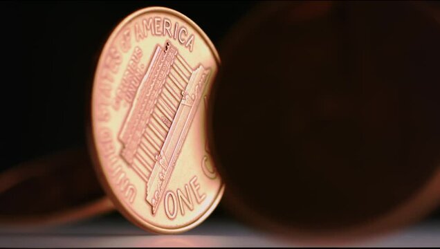 Super slow motion shot of pennies spinning around against a dark background