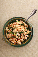 Cannellini white bean salad in a colorful green dish with copy space.
