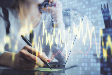 Double exposure of woman hands typing on computer and financial graph hologram drawing. Stock market analysis concept.