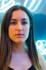 Young woman poses in front of a neon sign in a bar 