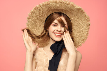 Portrait of a girl in a straw hat on a pink background emotions close-up beautiful face model pigtails