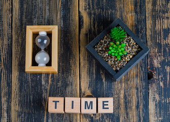 Business concept with time word on wooden cubes, hourglass, plant on wooden background flat lay.