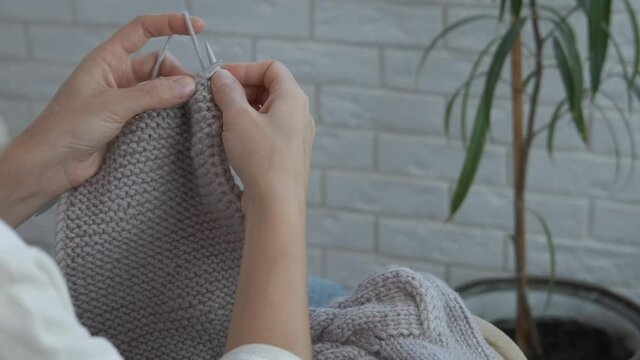 Knitted grey wool. A woman knit a handmade clothes from the soft grey wool.