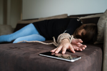 Close up on tied hands of unknown caucasian woman lying on bed at hotel room desperate trying to...