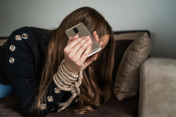 Close up on hands of unknown caucasian woman holding mobile phone with tied hands at hotel room...