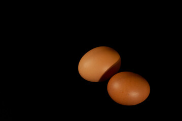 Two brown chicken eggs isolated on black background