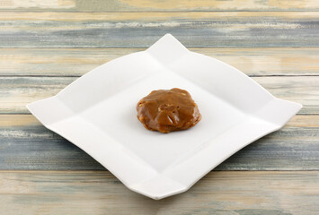 Creole praline caramel and pecan cluster on white snack plate on table