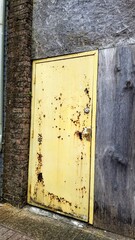 Old rusting yellow door and brick wall.