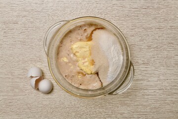 A mixture of milk, eggs, butter, sugar, salt, baking powder, vanillin, and yeast in a clear glass saucepan.