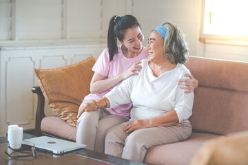 Obraz premium Cute Asian adult daughter embracing her mother with love in living room at home