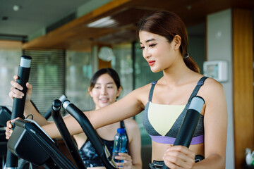 Fototapeta premium Beautiful woman work out on machine with trainer at gym.